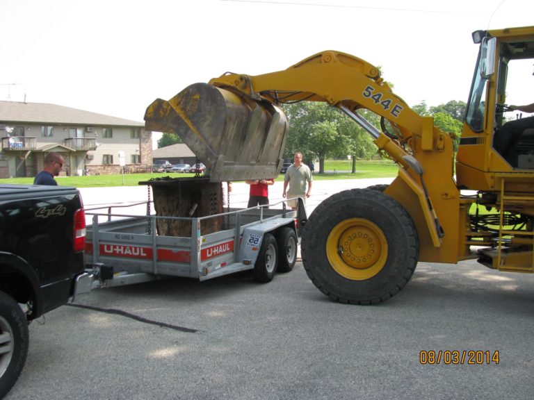 A loader is removing the steel beam from a trailer.
