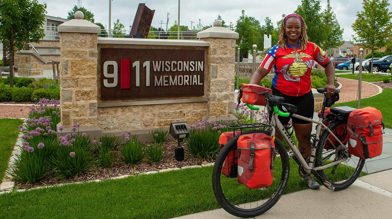US Marine Corps Veteran Tarra Gundrum standing in front of the Memorial with the bike she will ride to Washington D.C. from West Bend