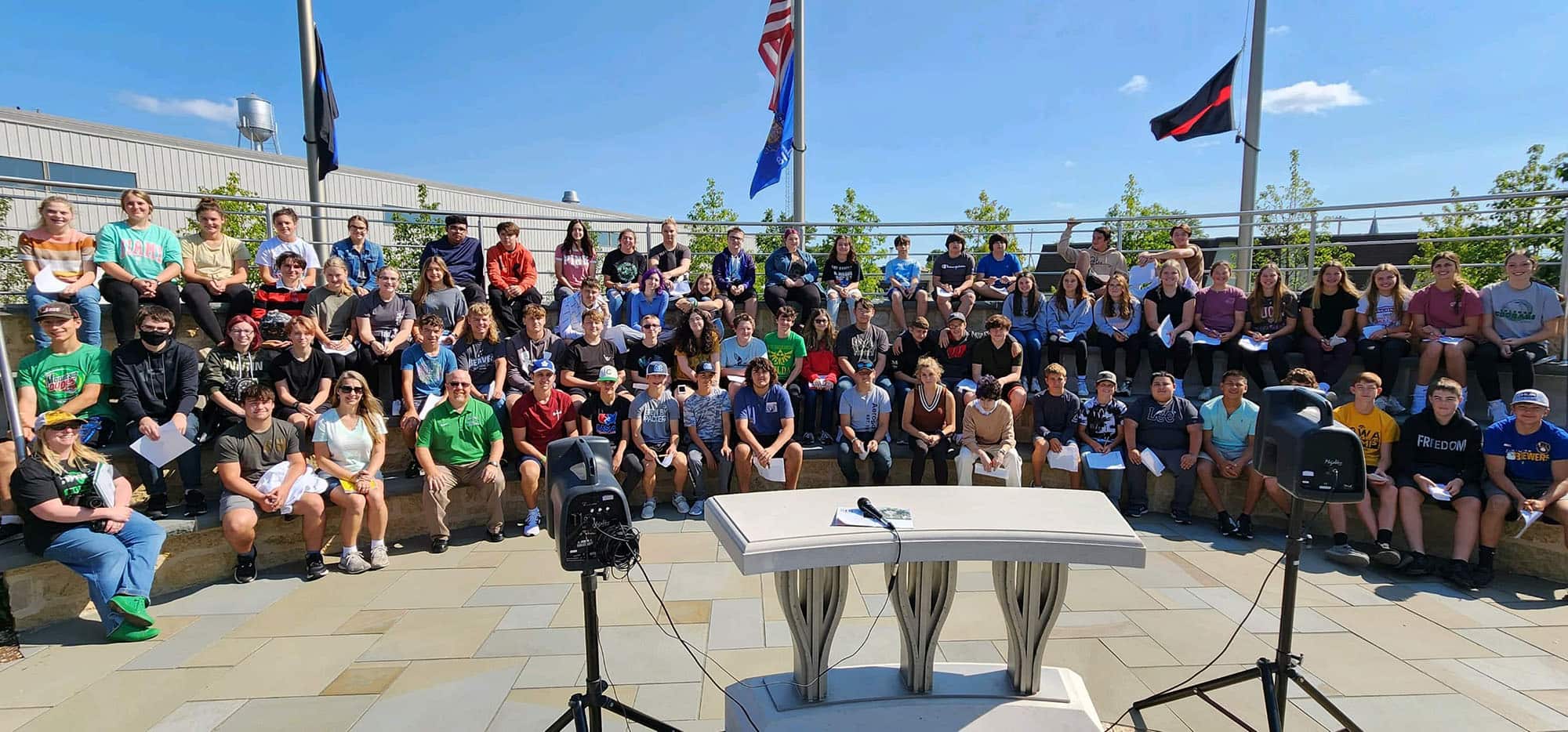 A group of 69 students from Coleman High School sitting on the rotunda of the Wisconsin 9-11 Memorial